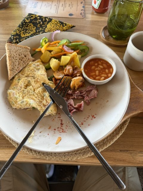 Frühstücksteller mit Omelett, Bohnen und Obst beim Sektfrühstück in der Savanne